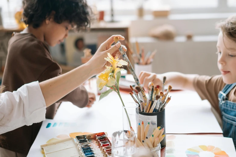 a couple of kids that are sitting at a table, trending on pexels, process art, holding paintbrushes, vase work, people at work, botanical drawing