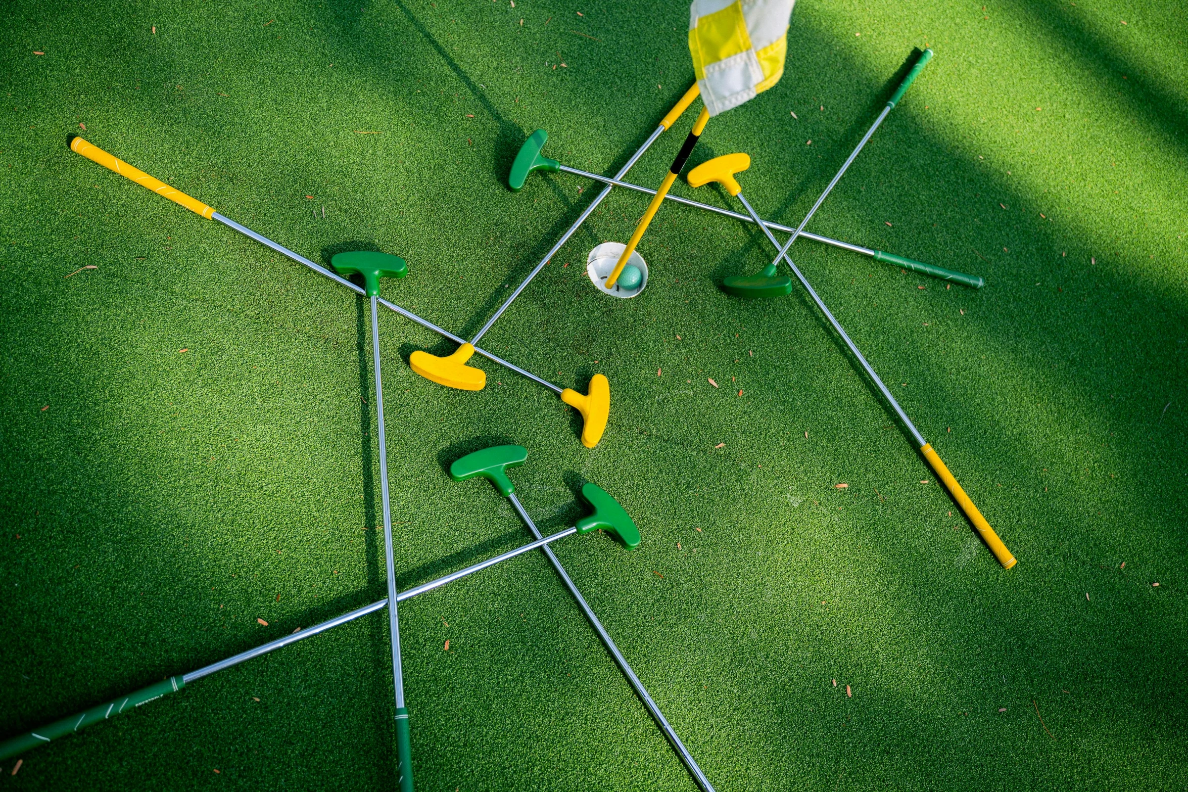 a group of golf clubs sitting on top of a green field, by Julia Pishtar, interactive art, maths, yellow and green, high angle close up shot, activity play centre