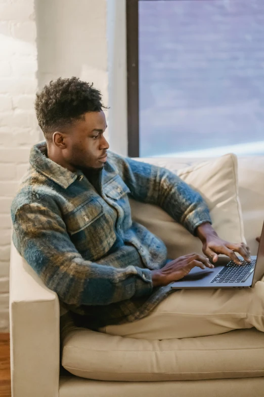 a man sitting on a couch using a laptop, trending on pexels, renaissance, jaylen brown, he is wearing a brown sweater, hunting, profile shot