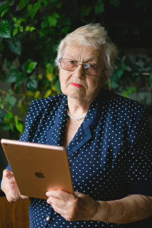 an older woman holding a tablet computer in her hands, a portrait, by Elsie Few, no cropping, annoyed, official screenshot, overlooking