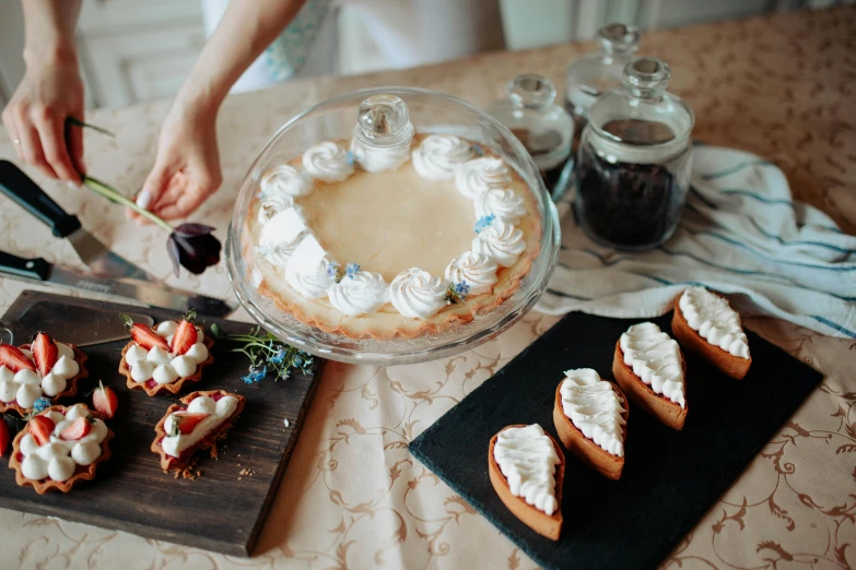 a person cutting a cake on top of a table, a still life, by Emma Andijewska, pexels contest winner, flan, fully decorated, with a white, glass domes