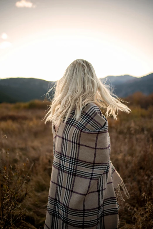 a woman wrapped in a blanket standing in a field, trending on unsplash, longer blond hair, back turned, wearing plaid shirt, set photo