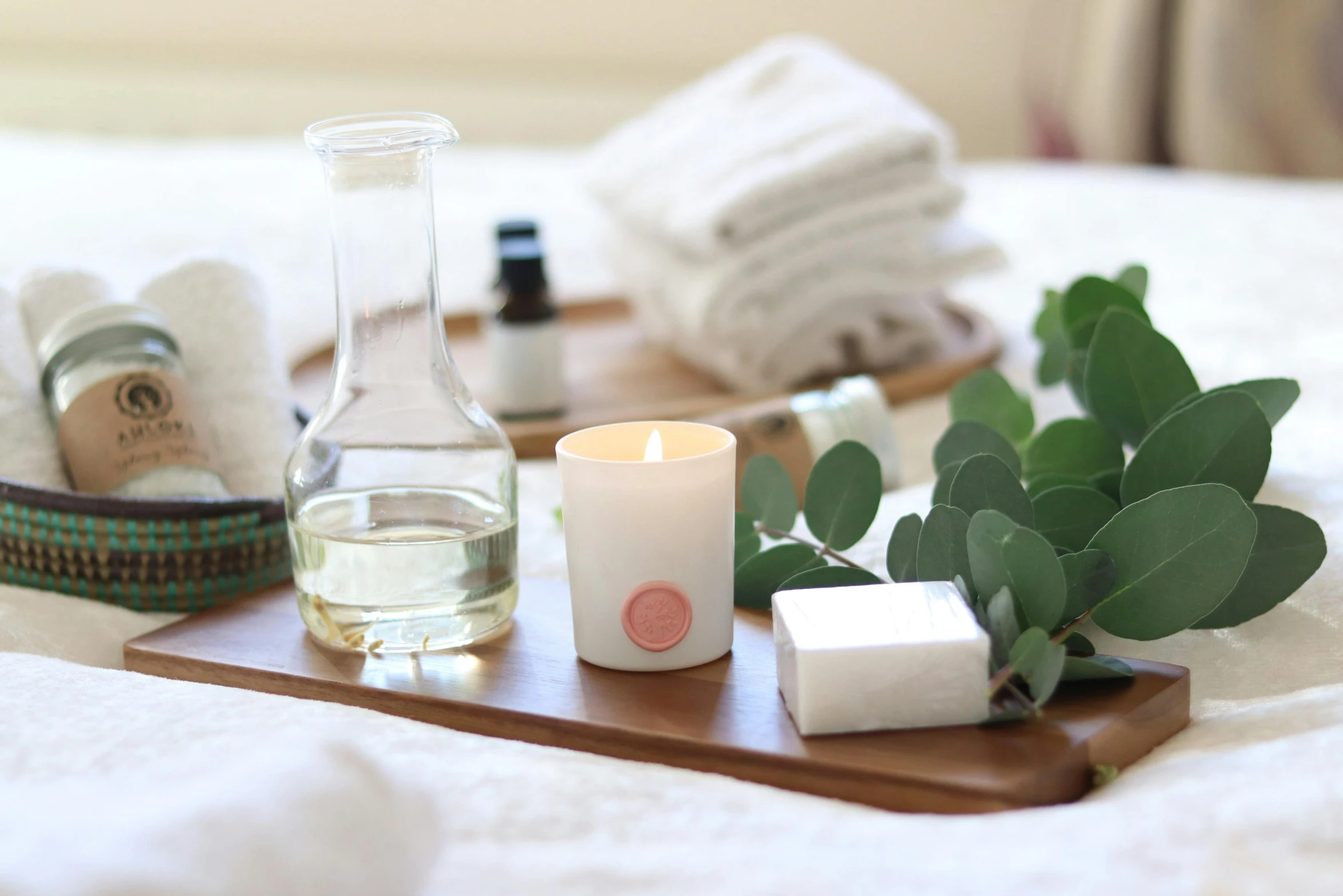 a wooden tray sitting on top of a bed next to a candle, a still life, inspired by Eden Box, unsplash, bubble bath, green and pink colour palette, on a white table, white