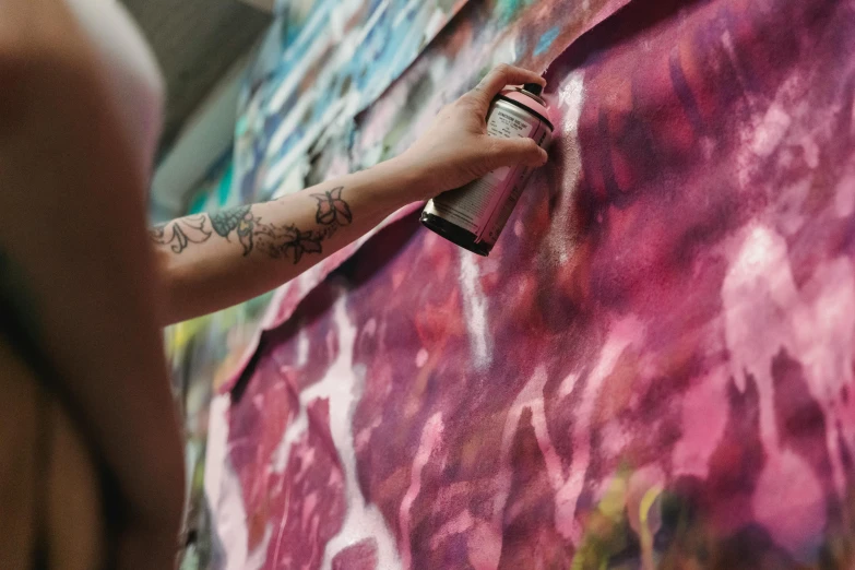 a person painting on a wall with a spray can, an airbrush painting, inspired by Julian Schnabel, trending on pexels, female emo art student, paper marbling, painting on silk, body covered in floral tattoos