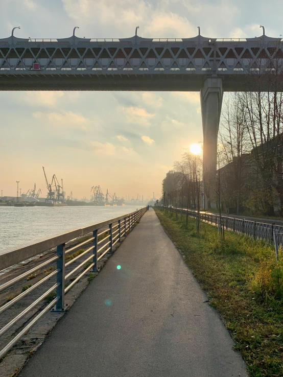 a view of a bridge over a body of water, a picture, inspired by Jan Müller, happening, tree-lined path at sunset, industrial surrounding, 2022 photograph, port city