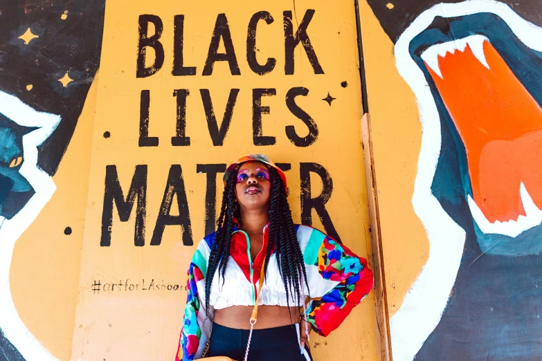 a woman standing in front of a black lives matter sign, black arts movement, 🦩🪐🐞👩🏻🦳, vibrant hues, outlive streetwear collection, tourist photo