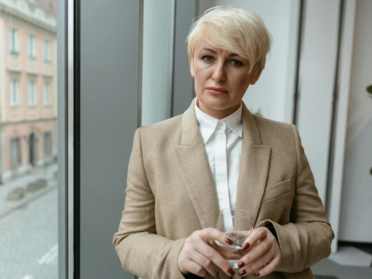 a woman standing in front of a window holding a cell phone, bleached blonde short hair, serious business, thumbnail, multiple stories