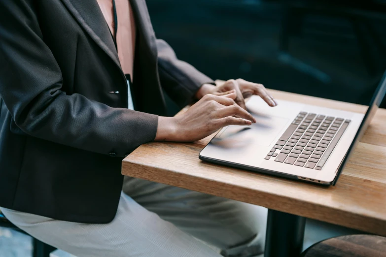 a woman sitting at a table typing on a laptop, by Carey Morris, trending on pexels, wearing a blazer, worksafe. instagram photo, excellent detail, thumbnail