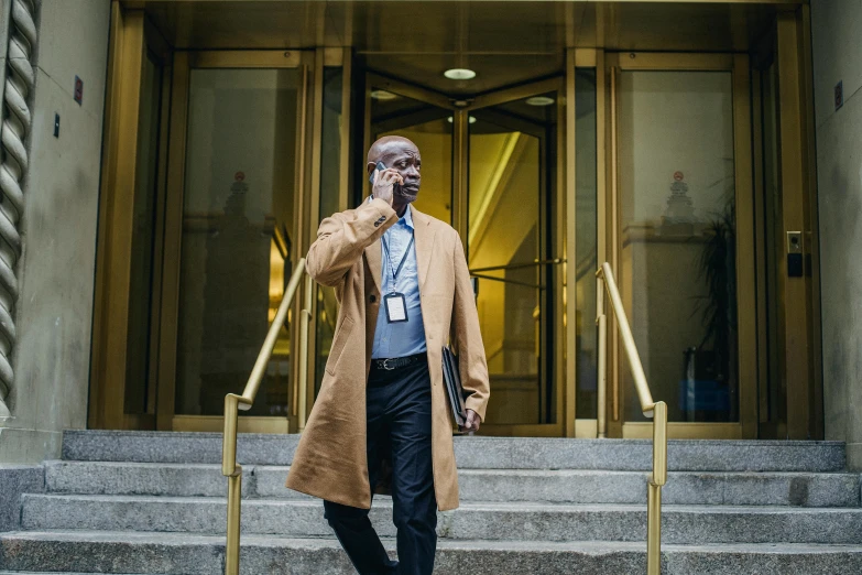 a man standing in front of a building talking on a cell phone, henry dorsett case, healthcare worker, hbo, high-res