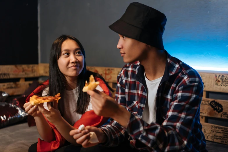 a man and a woman sitting on a couch eating pizza, trending on pexels, realism, with black beanie on head, asian female, male teenager, reaching out to each other