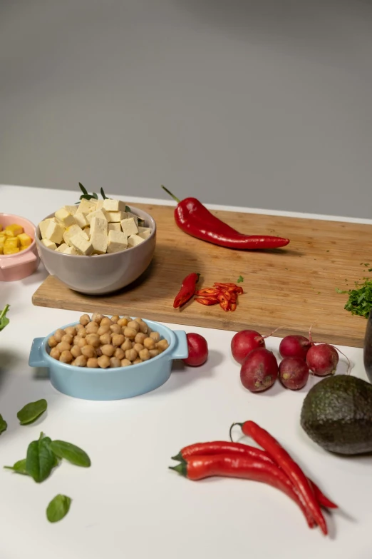 a table topped with lots of different types of food, a still life, inspired by Ceferí Olivé, unsplash, on grey background, chili, natural wood top, cutting a salad