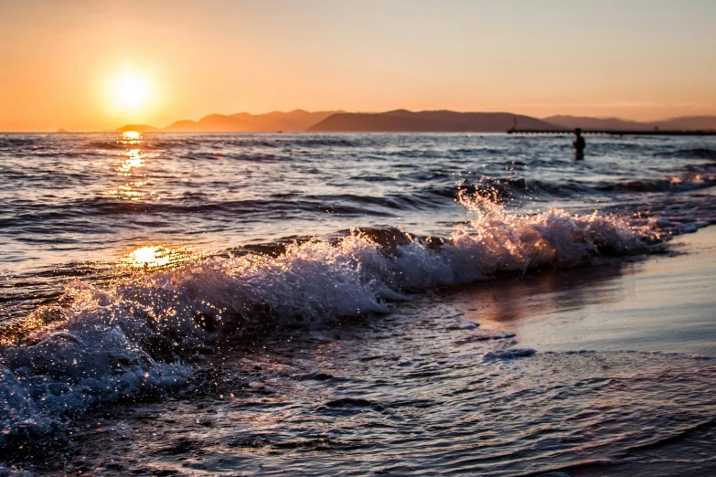 a person riding a surfboard on top of a wave, pexels contest winner, romanticism, sunset on the beach, wellington, sparkling in the sunlight, which shows a beach at sunset