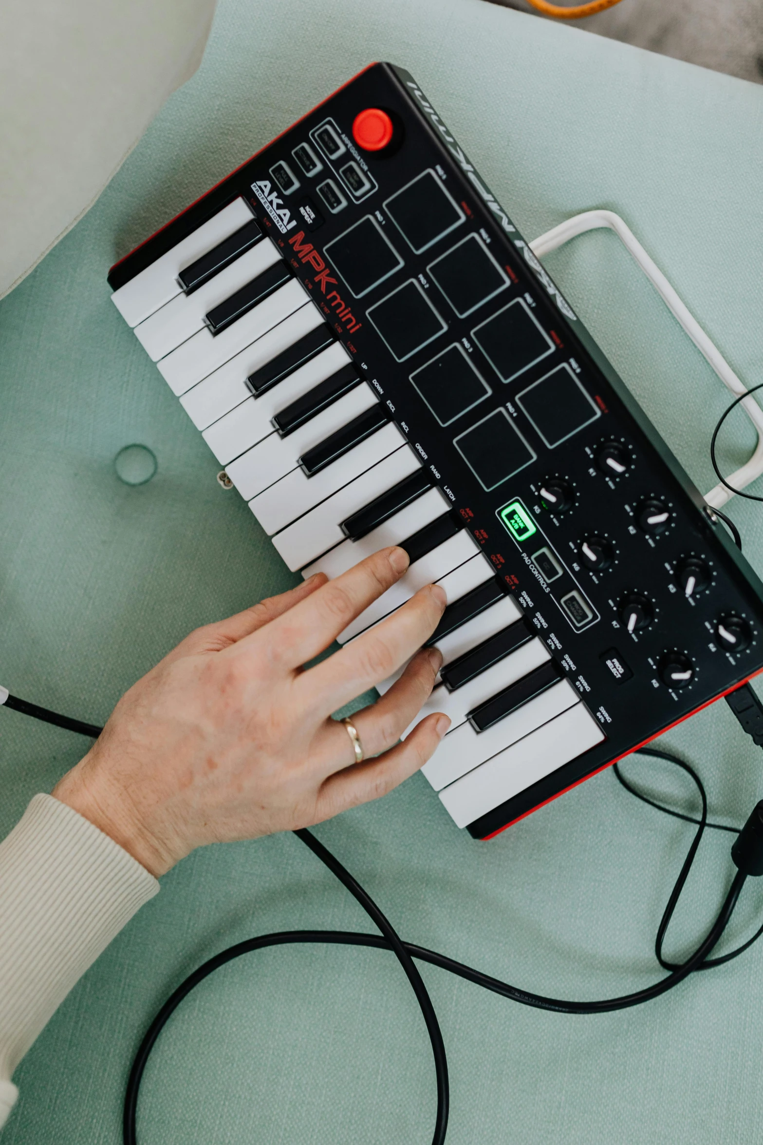 a person sitting at a table with a keyboard, an album cover, by Julia Pishtar, unsplash, synthetism, holding controller, circuit bent synthesis, small gadget, slightly red