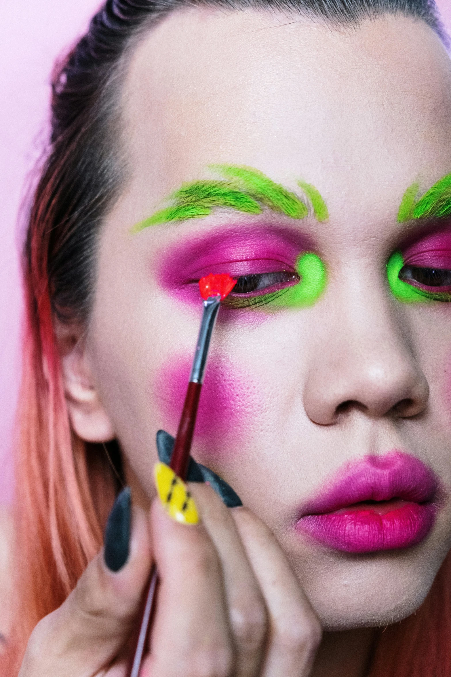 a close up of a person with pink and green makeup, an album cover, inspired by Bernd Fasching, trending on pexels, putting makeup on, bushy eyebrows, green bright red, having fun. vibrant