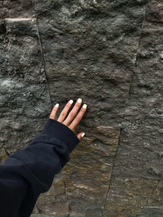 a person standing in front of a stone wall, veiny hands, subreddit / r / whale, nature aesthetics, background image