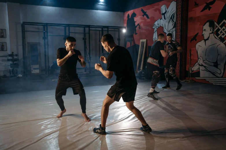 a couple of men standing on top of a dance floor, mma southpaw stance, in a workshop, background image, [ theatrical ]