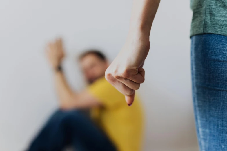 a woman holding the hand of a man in a yellow shirt, trending on pexels, figuration libre, violence, background image, sits on a finger, out of focus