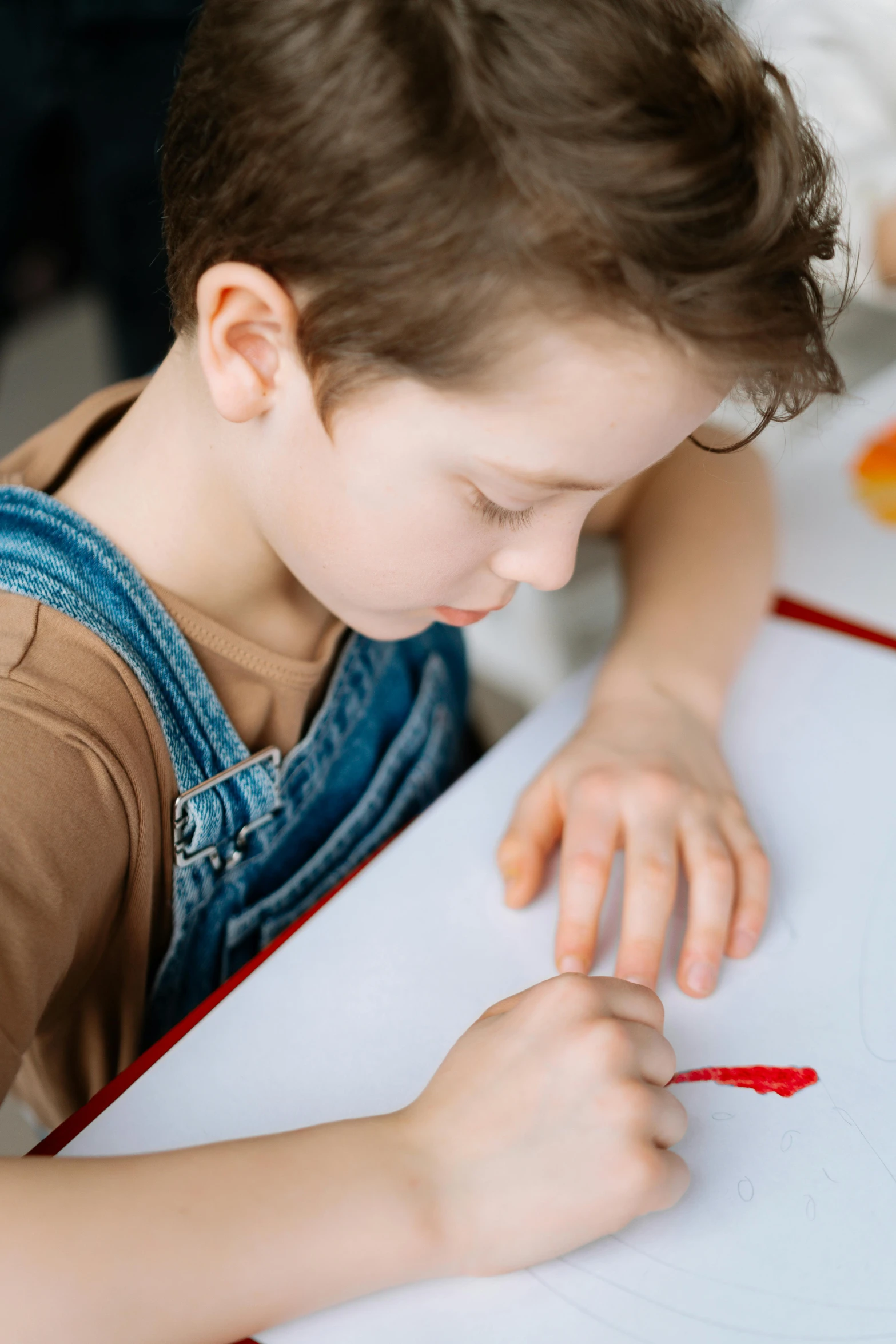 a little boy that is sitting at a table, a child's drawing, pexels, red writing, over his shoulder, carefully crafted, soft texture