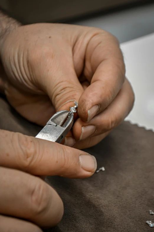 a person cutting a piece of leather with a pair of scissors, an engraving, arbeitsrat für kunst, bvlgari jewelry, silver，ivory, grey, restoration