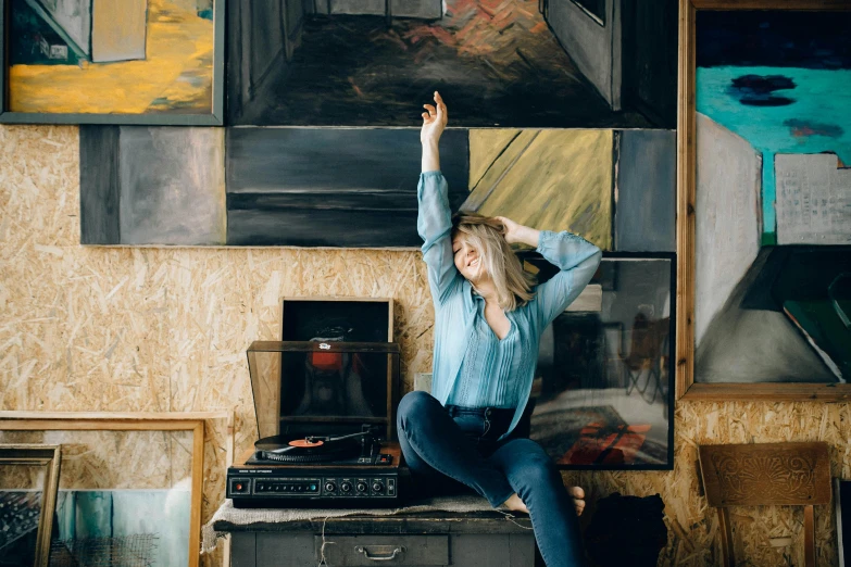 a woman sitting on top of a table in front of a painting, an album cover, pexels contest winner, 15081959 21121991 01012000 4k, in an attic, everyone having fun, julia gorokhova