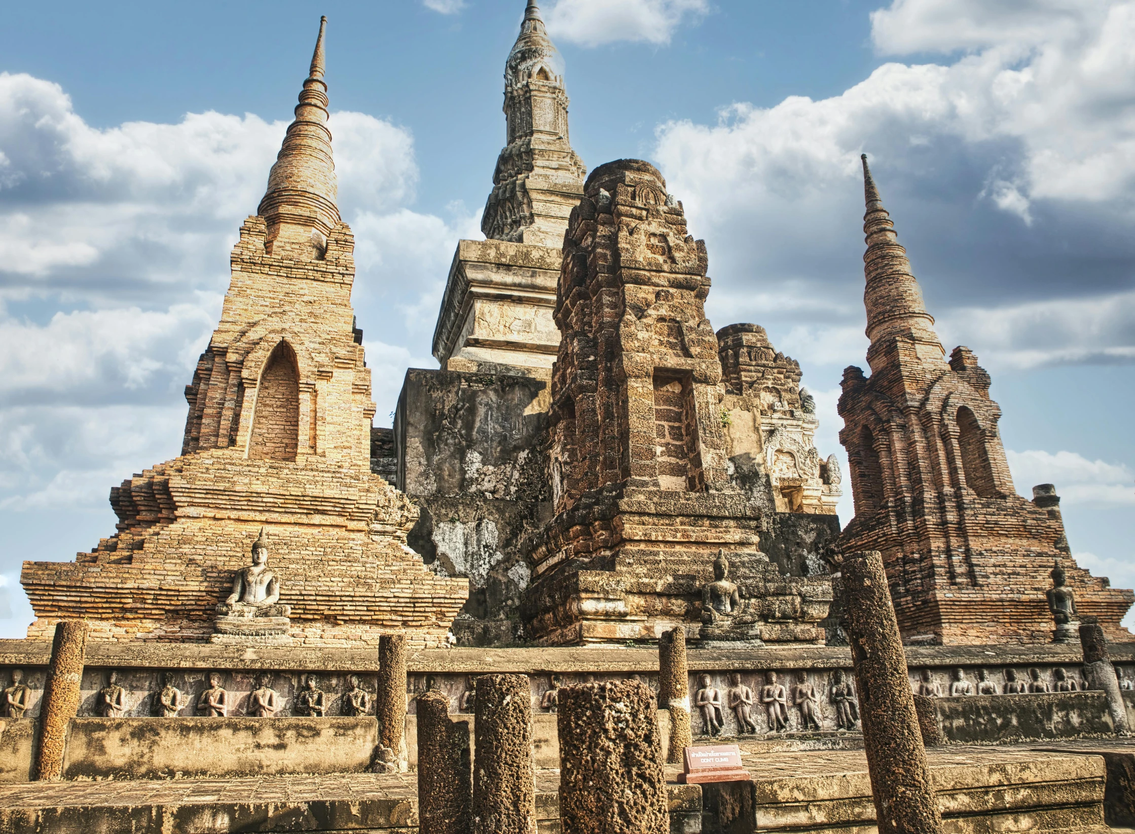 a group of tall buildings sitting on top of a lush green field, baroque, sukhothai costume, dry archways and spires, ruined, intricate image