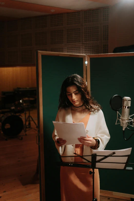 a woman standing in front of a microphone in a recording studio, an album cover, by Sebastian Vrancx, trending on pexels, yael shelbia, sheet music, actress, set photograph