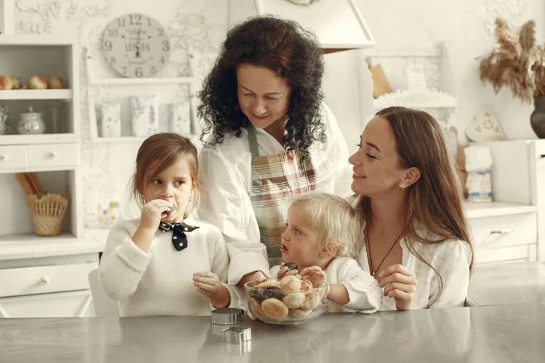 a woman and two children sitting at a table eating doughnuts, a picture, by Adam Marczyński, pexels contest winner, cute kitchen, gif, white, ladies