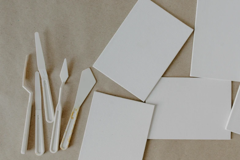 a bunch of pieces of paper sitting on top of a table, a minimalist painting, inspired by Rachel Whiteread, unsplash, knives, whiteboards, spatula, cream and white color scheme