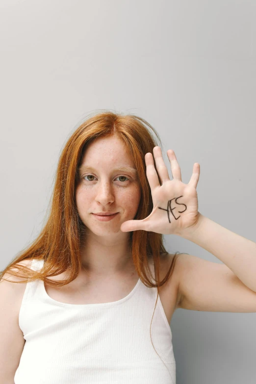a woman making a peace sign with her hands, an album cover, inspired by Kaja Foglio, trending on pexels, ( redhead, patricia piccinini, letter s, teenage female schoolgirl