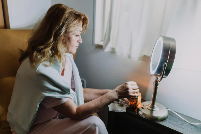 a woman sitting on a chair in front of a mirror, lighting her with a rim light, someone in home sits in bed, profile image, thin healing glowing devices