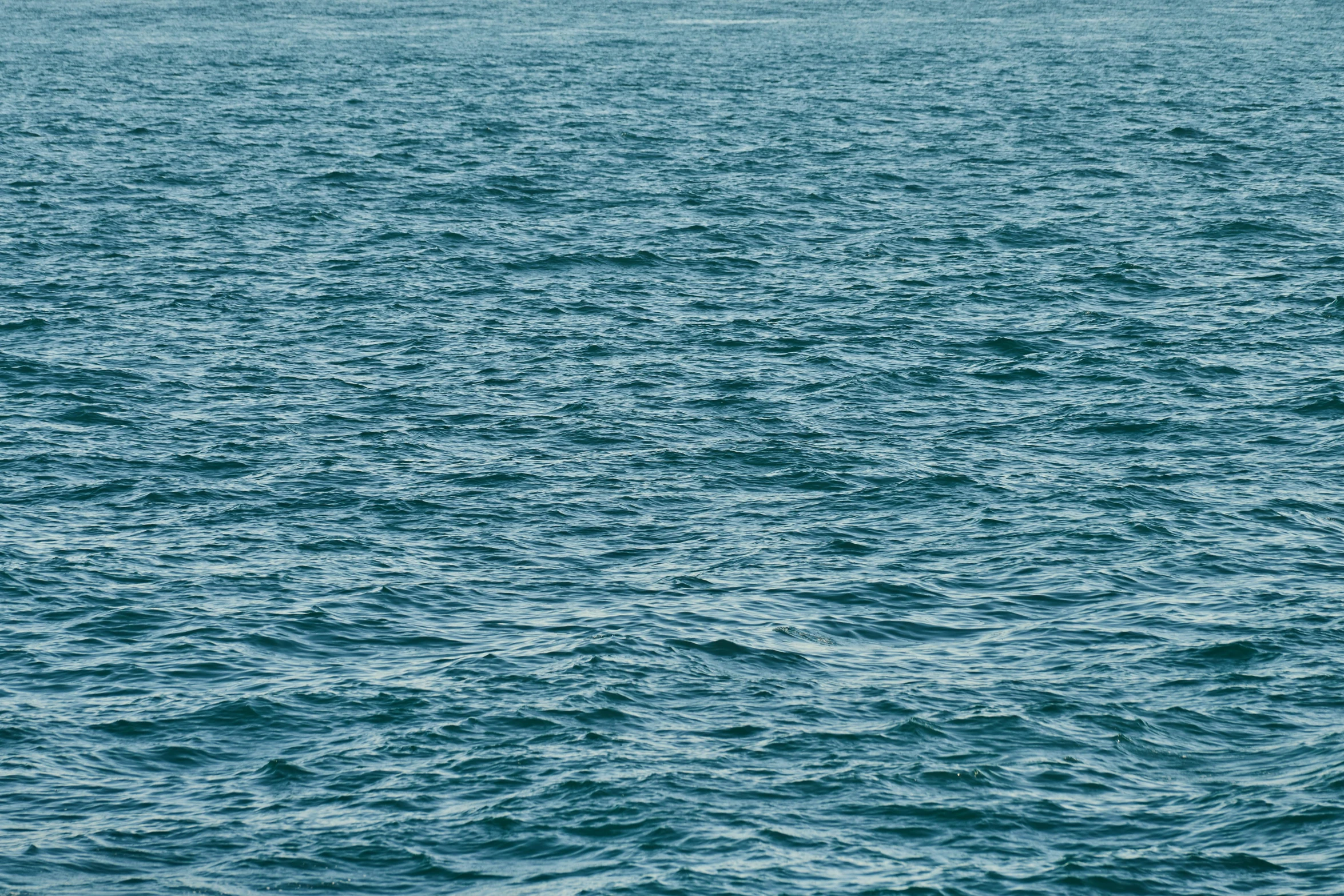 a large body of water with a boat in the distance, an album cover, inspired by Vija Celmins, unsplash, hurufiyya, ocean pattern, ignant, vibrant but dreary blue, andres gursky