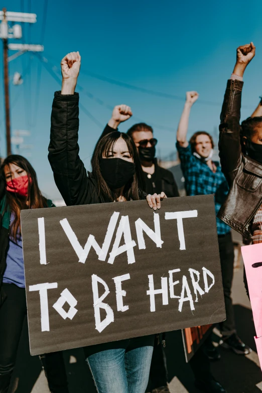a group of people holding signs that say i want to be heard, trending on pexels, masked, photo of young woman, controversial, oktane