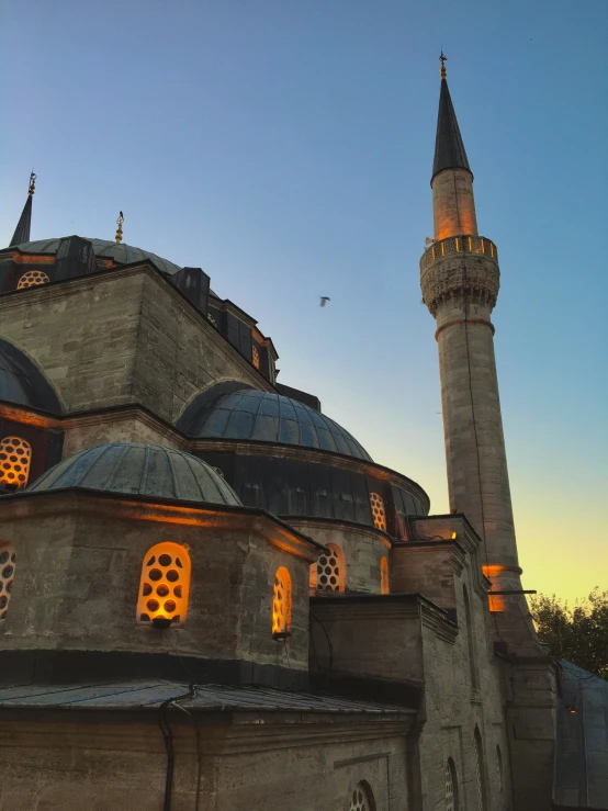 a large building with a clock on top of it, an album cover, inspired by Altoon Sultan, pexels contest winner, hurufiyya, late summer evening, domes, blue, backlighted