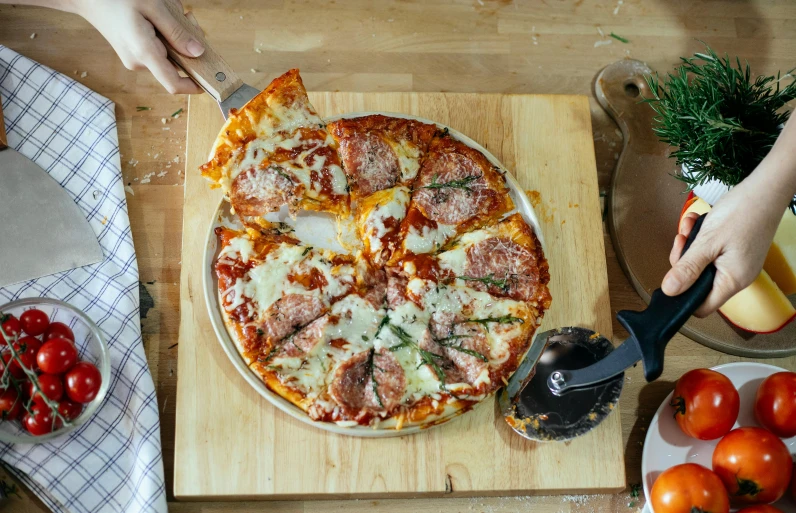 a pizza sitting on top of a wooden cutting board, pexels contest winner, cheese and salami on the table, wide high angle view, thumbnail, holding close