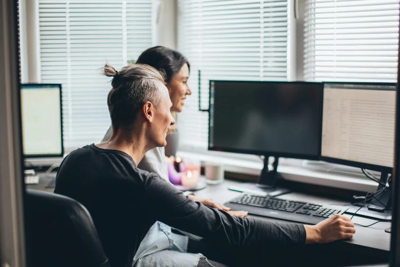 a couple of people that are sitting in front of a computer, trending on pexels, looking around a corner, healthcare, home office, non-binary