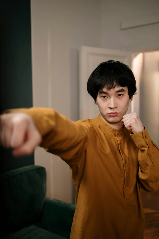 a man standing in a living room holding a remote control, inspired by Wang Zhongyu, pexels contest winner, hyperrealism, in a fighting stance, in orange clothes) fight, t pose, asian male