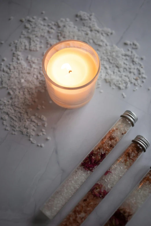 a couple of spoons sitting next to a candle, salt effects, botanicals, rectangle, a close up shot