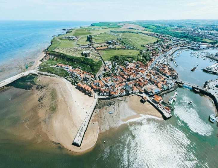 a large body of water next to a beach, by Julian Hatton, pexels contest winner, renaissance, medieval coastal village, aerial, yorkshire, isaac newton