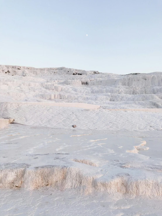 a man riding a snowboard on top of a snow covered slope, a marble sculpture, inspired by Elsa Bleda, trending on unsplash, in dusty open pit mine, white travertine terraces, bathed in moonlight, pink water in a large bath