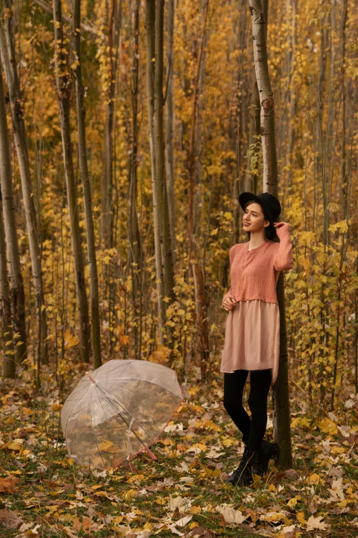 a woman standing next to a tree with an umbrella, inspired by Oleg Oprisco, unsplash, in the autumn forest, fashion shoot 8k, a handsome, u