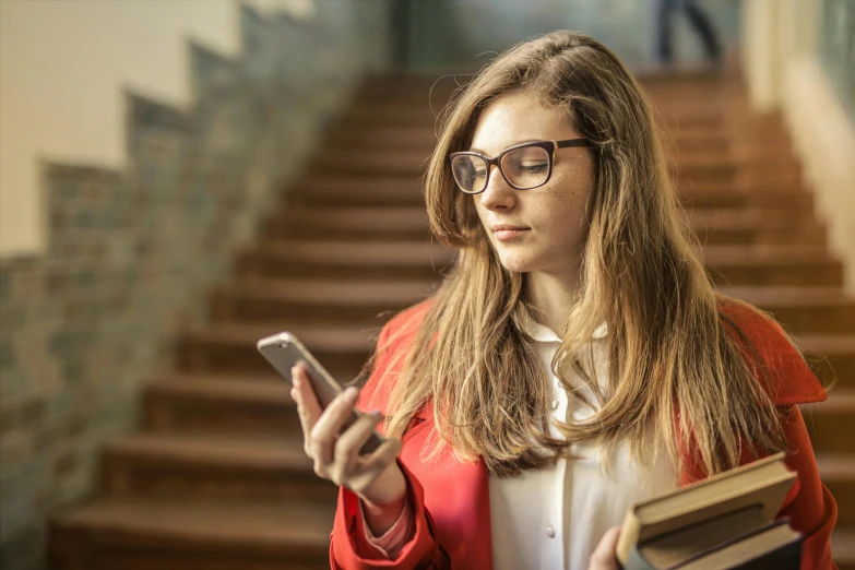 a woman in glasses holding a book and a cell phone, a picture, by Alice Mason, shutterstock, happening, high school girls, instagram post, university, aged 13