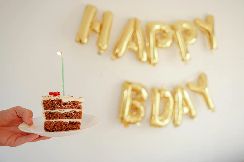 a person holding a plate with a piece of cake on it, an album cover, by Julia Pishtar, pexels, party balloons, background image, | 35mm|, happy birthday