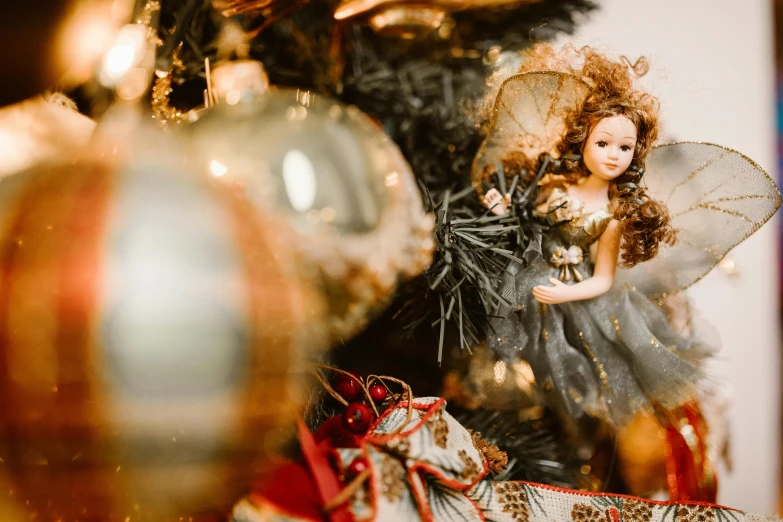 a close up of a doll on a christmas tree, by Julia Pishtar, pexels contest winner, baroque, black and gold colors, beautiful girl, gif, fan favorite