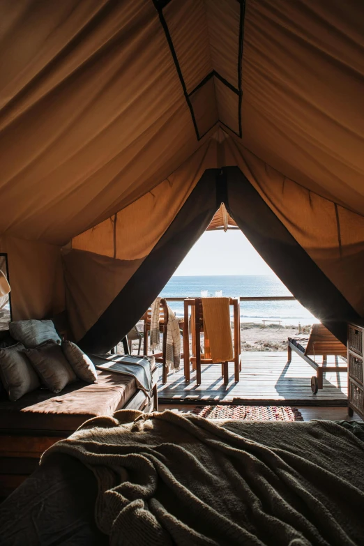 a bed sitting inside of a tent next to a window, beachfront, balcony, expansive cinematic view, cabin