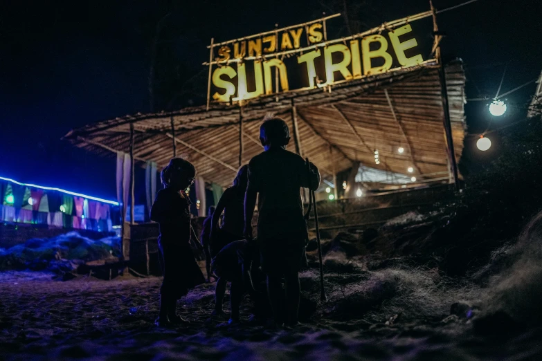 a couple of people that are standing in the snow, by Nick Fudge, unsplash contest winner, sumatraism, neon sign, suns rays, tribe members attacking, sitting on the beach at night