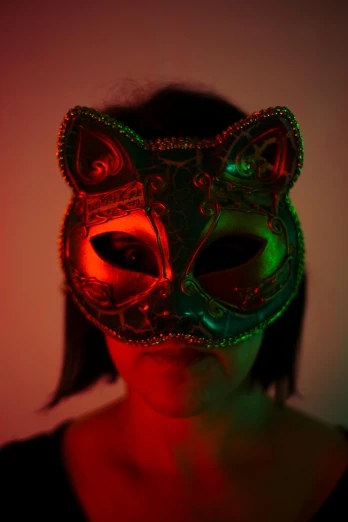 a woman wearing a green and red mask, an album cover, inspired by Elsa Bleda, pexels, beautiful neon cats, vantablack chiaroscuro, taken in the late 2010s, frontal shot