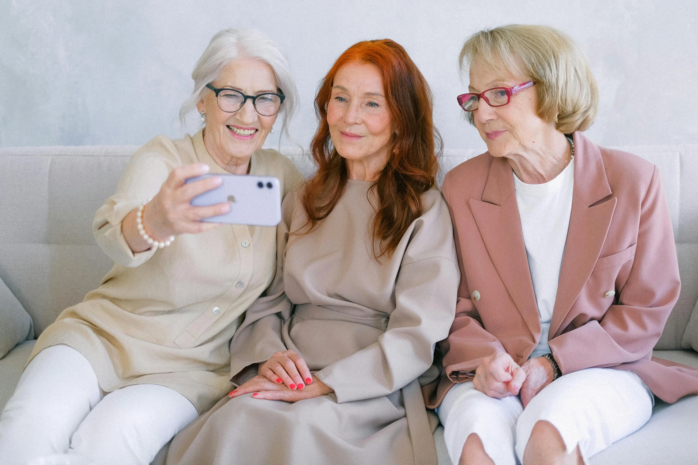 three women sitting on a couch taking a selfie, trending on pexels, an old lady with red skin, a very macular woman in white, professional modeling, woman with red hair