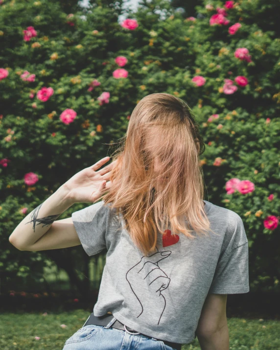 a woman sitting on top of a lush green field, a polaroid photo, inspired by Elsa Bleda, trending on unsplash, rose hair, embroidered shirt, on a gray background, greeting hand on head