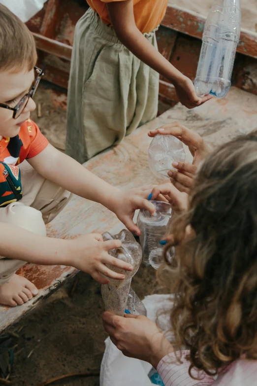 a group of young children standing next to each other, pexels contest winner, process art, plastic bottles, playing with the water, textured, beakers