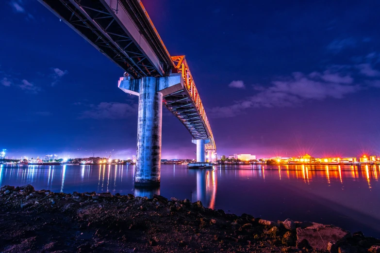 a bridge over a body of water at night, by Jason Felix, pexels contest winner, blue and orange lighting, okinawa japan, infrastructure, instagram photo